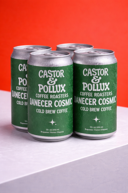 Green and silver cans of Castor & Pollux Danecer Cosmic cold brew coffee on a white and orange background.